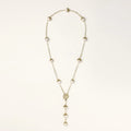 Gold-plated lariat necklace with baroque pearls and textured caps on cream background, showing adjustable Y-shaped design.